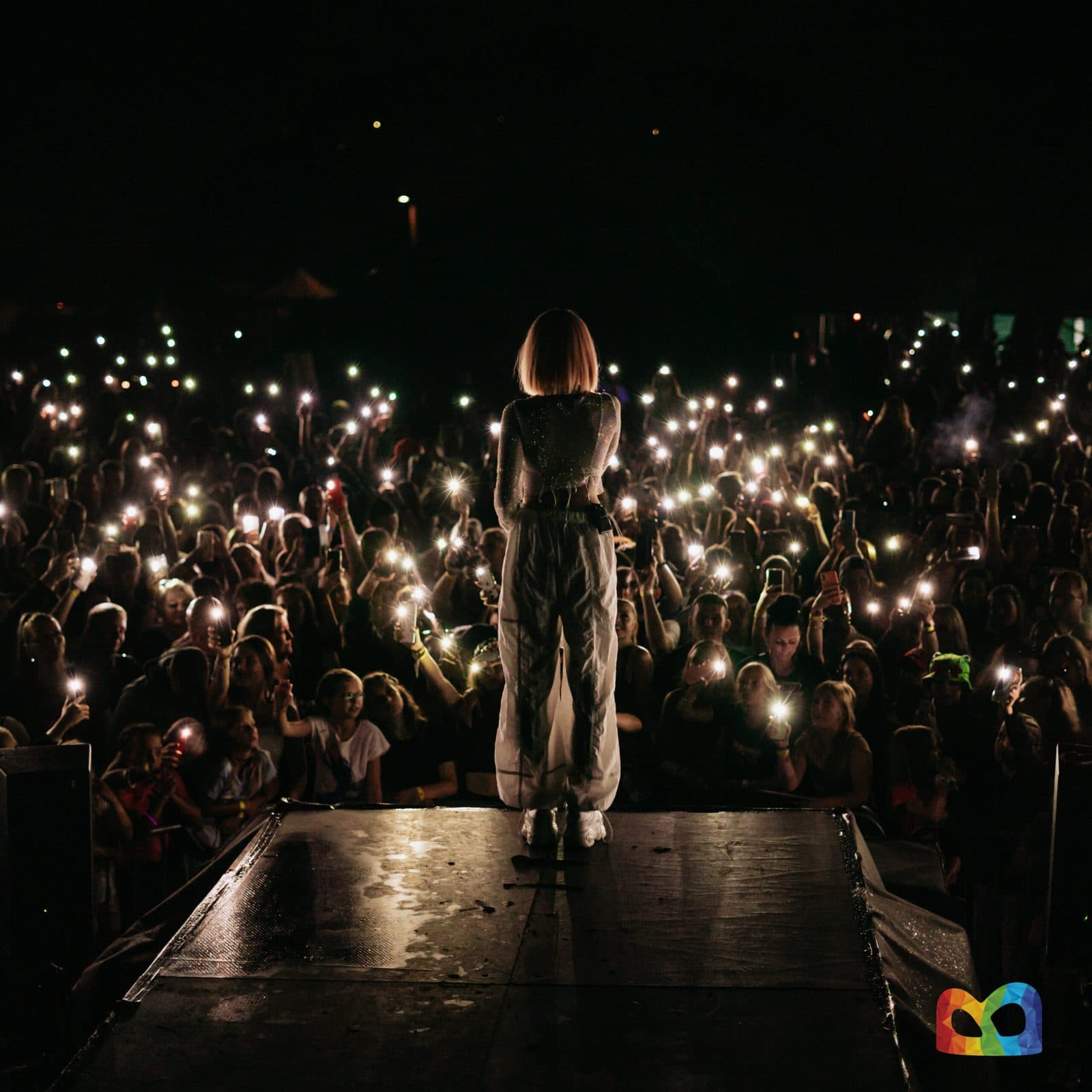 Zpěvačka na pódiu festivalu Baška žije za soumraku, dav svítí mobily